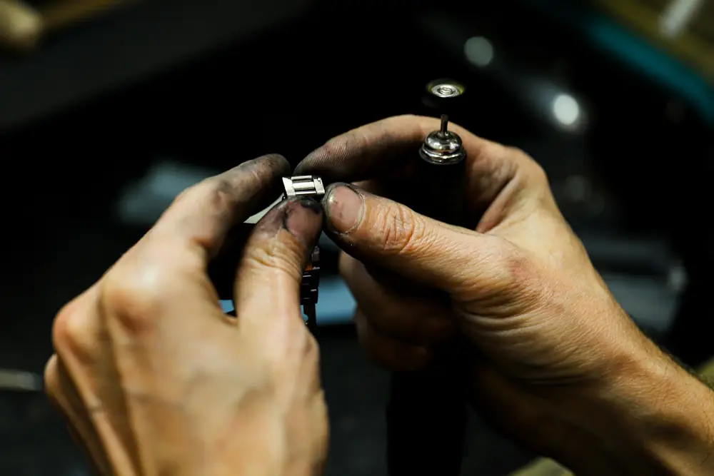 A jeweler polishing a ring by hand at the bench
