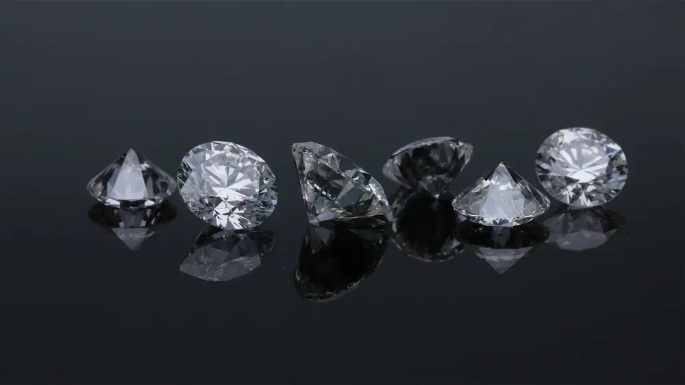 A row of faceted diamonds on a reflective black surface