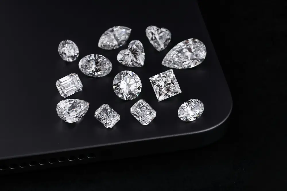 Loose diamonds in different shapes laid out on a black surface