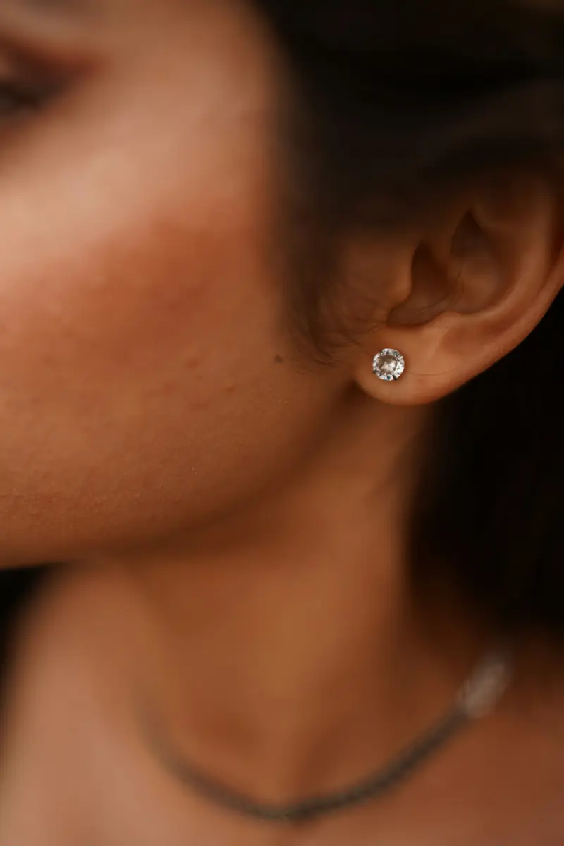 Close view of an ear wearing a single diamond stud earring