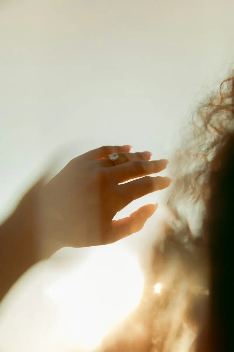 A hand wearing a diamond ring, lit from behind