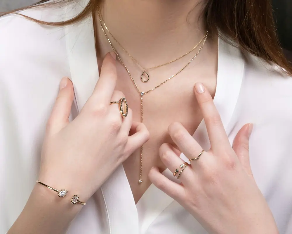 Hands wearing diamond rings, a bracelet and fine necklaces