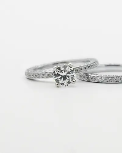 A diamond solitaire engagement ring beside its matching pavé wedding band on a white ground
