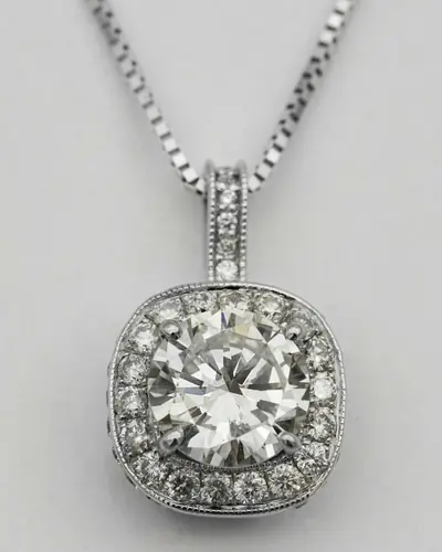 A round diamond pendant in a cushion-shaped halo with a milgrain edge and diamond bail