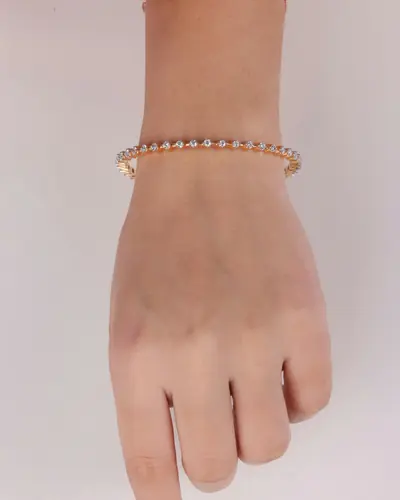 A single row diamond tennis bracelet worn on a wrist