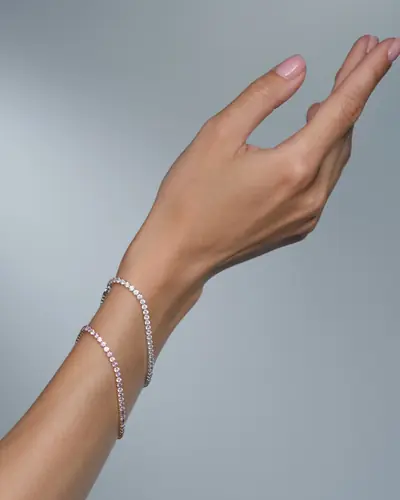 Two slim diamond tennis bracelets worn together on a forearm