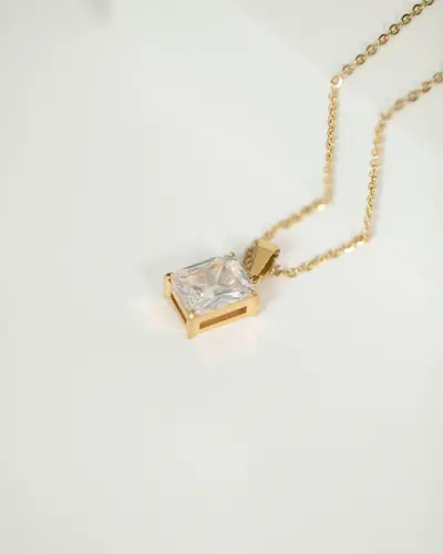 A square diamond solitaire pendant on a fine chain, on a white ground